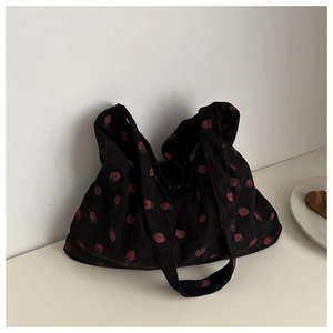 Detalle del bolso tote de pana negra con estampado de fresas rojas y tela texturizada