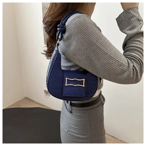 Detail of dark blue hobo bag with crocodile texture and gold geometric metal buckle