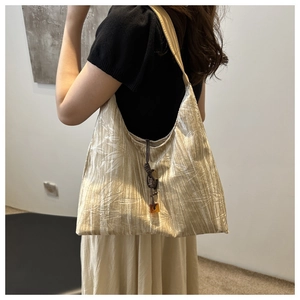 Détail du sac bandoulière en soie champagne avec jacquard bambou et pendentif ambré