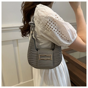 Detail of grey crocodile embossed hobo bag with gold metal buckle on a shoulder strap