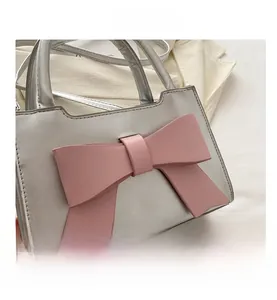 Detail view of silver mini handbag with a 3D pink bow and metallic PU leather finish