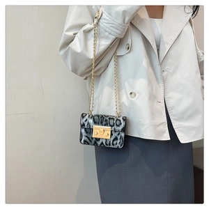 Dettaglio mini borsa leopardata con tracolla a catena dorata su trench beige