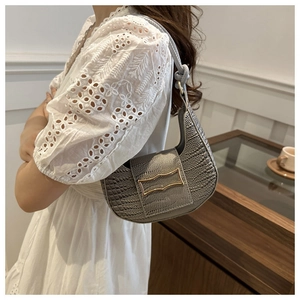 Close-up of gray crocodile pattern leather handbag with gold H buckle on a wooden table