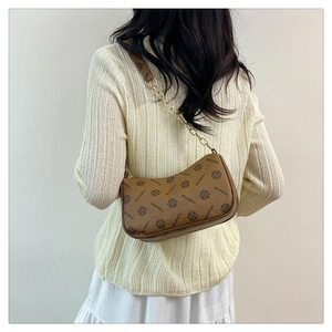 Détail d'un sac demi-lune en cuir marron avec motif monogramme et bandoulière chaîne dorée