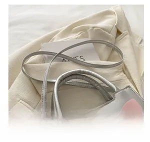 Detail showing the adjustable shoulder strap and pink bow on silver crossbody handbag