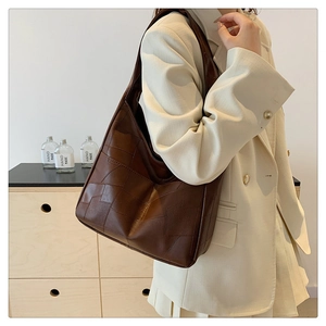 Close-up of brown patchwork leather tote bag styled with a professional beige suit