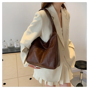 Detailed view of dark brown oversized shoulder bag with geometric patchwork design texture