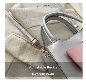Detail of adjustable gold buckle on a silver textured crossbody bag with pink leather trim