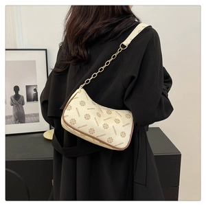 Détail d'un sac demi-lune crème avec imprimé floral vintage et bandoulière en chaîne