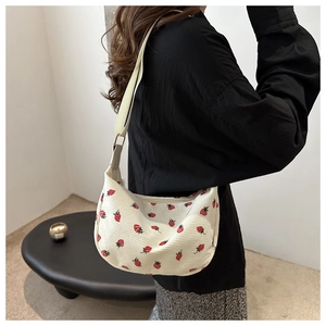 Gros plan d'un sac demi-lune en velours côtelé blanc avec imprimé fraises sur modèle