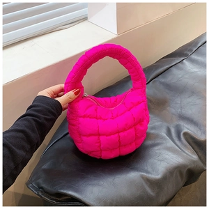 Close-up of bright pink quilted puffer handbag with square pattern and zipper detail