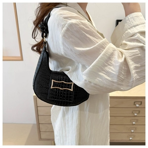 Detail showing black crocodile texture on minimalist half-moon bag with gold metal buckle