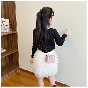 Fillette portant un sac à main rose scintillant à perles avec une jupe en tulle multicouche