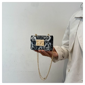 Dettaglio di una mini borsa a catena leopardata con fibbia dorata e consistenza morbida