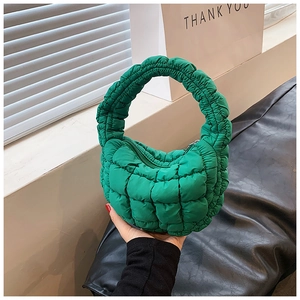 Detail of green quilted cloud handbag with square texture and round top handle