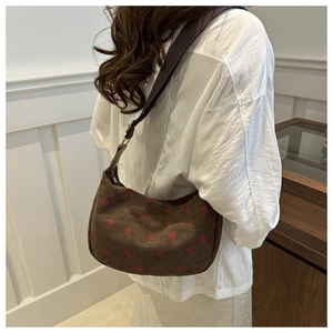 Détail du sac hobo en velours côtelé marron avec broderie de coeurs rouges et sangle