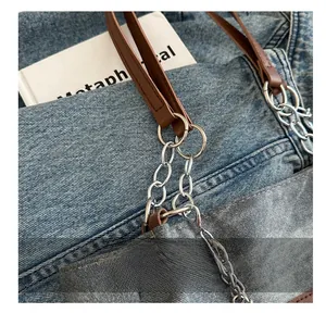 Dettaglio della borsa tote in denim blu con tracolla in pelle e catena argentata