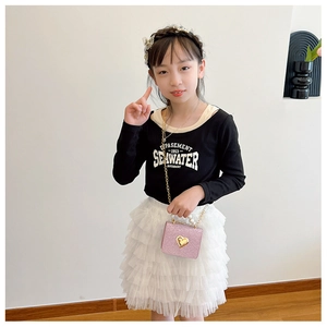 Fillette en t-shirt noir et jupe tutu avec mini sac rose à paillettes et cœur doré