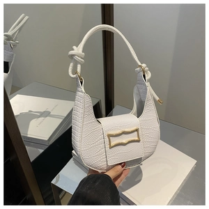 Detailed macro view of white crocodile embossed texture on a crescent shoulder bag