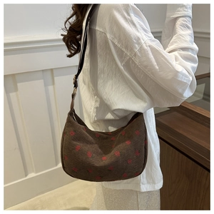 Détail du sac hobo en velours côtelé marron avec broderie fraise et bandoulière réglable