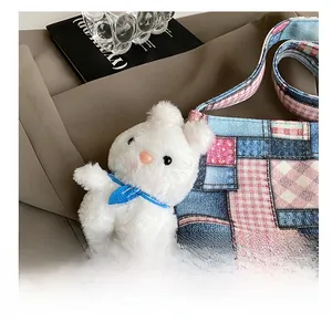 Close-up of white plush bunny charm with blue bow on a casual denim tote bag accessory