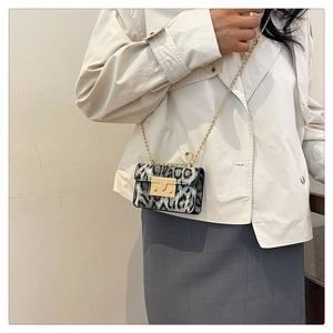 Dettaglio di una mini borsa a tracolla leopardata con catena dorata su modella