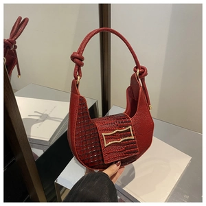 Close-up of red retro underarm bag featuring crocodile pattern and golden metal buckle