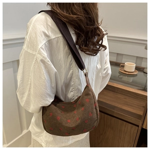 Détail du sac bandoulière en velours côtelé marron avec motifs rouges et large sangle