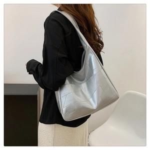 Silver geometric patchwork shoulder bag shown on model in a minimalist fashion studio