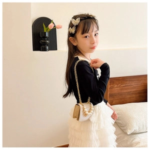 Détail du sac à main pailleté doré pour fille avec poignée en perles et pinces à cheveux papillon