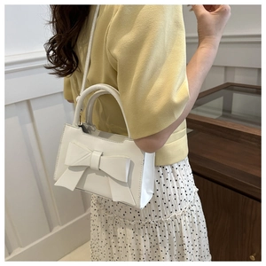 Detailed view of a white PU leather crossbody bag with a large decorative bow