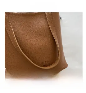 Gros plan du sac seau marron avec texture grainée et logo Fashion Bags embossé