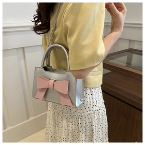 Silver PU leather handbag with large pink bow shown on model with polka dot skirt