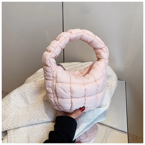 Detailed close-up of pink quilted cloud bag texture and handle on a reflective surface