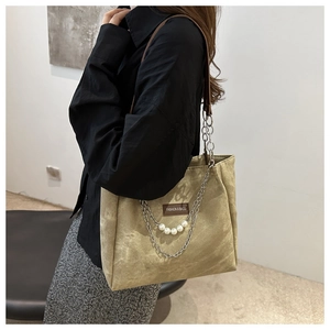 Dettaglio della borsa tote in pelle scamosciata kaki con catene e ciondoli di perle