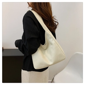 Detailed back view of a cream hobo shoulder bag with geometric texture worn by a model
