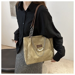 Dettaglio della borsa tote kaki con catena in metallo ed eleganti ciondoli di perle bianche