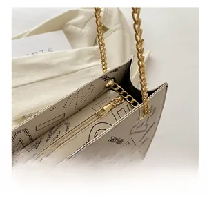Close-up of golden zipper and leather texture on a cream shoulder bag with logo print