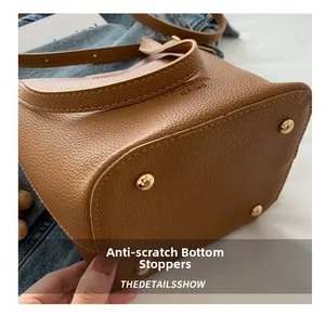 Détails des clous de protection dorés et texture de cuir sur le sac seau marron foncé