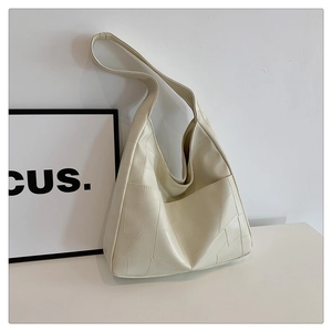 Detailed view of cream-colored hobo bag with geometric stitching and wide shoulder strap