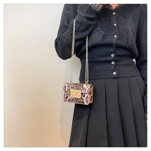 Dettaglio di una mini borsa leopardata con catena e fibbia d'oro su vestiti neri