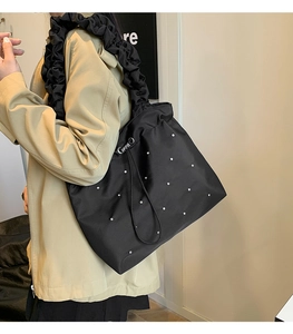 Dettaglio della borsa tote nera con spalline arricciate stile scrunchie e decori di perle