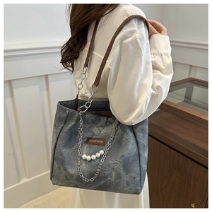 Dettaglio della borsa tote grigia vintage con catena metallica e perle sulla spalla