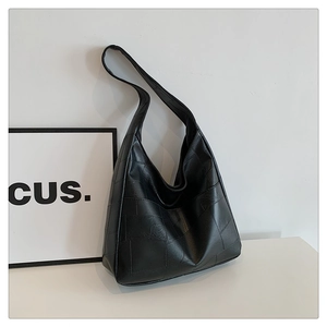 Detail of black large capacity hobo bag featuring square quilted texture and wide shoulder strap