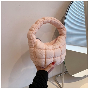 Close-up of peach pink puffer cloud bag with quilted square texture and circular handle