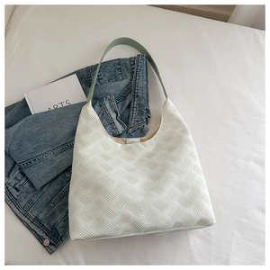 Detail of white textured puff woven tote bag with mint green handle on white bedding