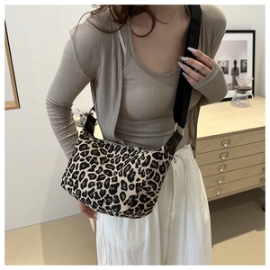Gros plan du sac bandoulière léopard avec sangle noire sur une tenue en maille beige