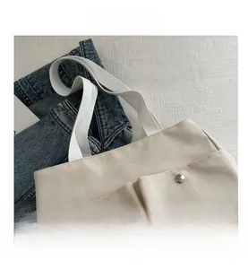 Close-up of cream canvas tote bag with metal rivets and sturdy woven handles