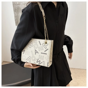 Detailed view of cream leather shoulder bag with black letter prints and metal chain strap