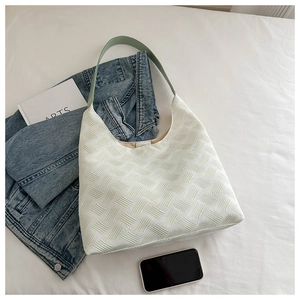 Detail of white woven texture shoulder bag with light green strap on a lifestyle backdrop